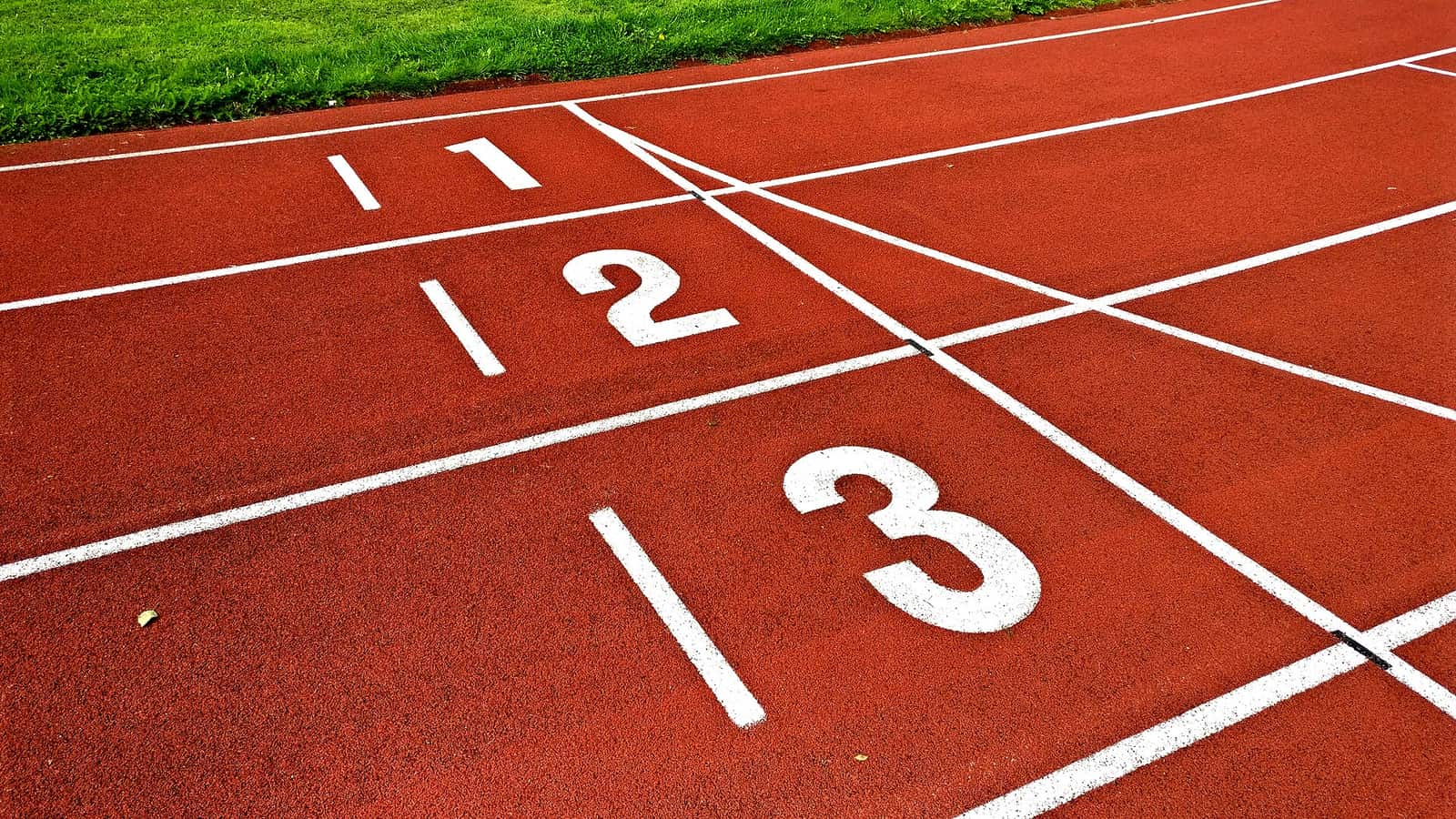 Les lignes de départ des couloirs 1, 2 et 3 d'une piste d'athlétisme rouge