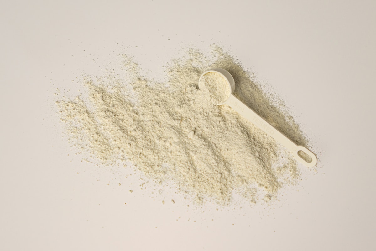 Dosette et poudre de complément alimentaire sur fond clair