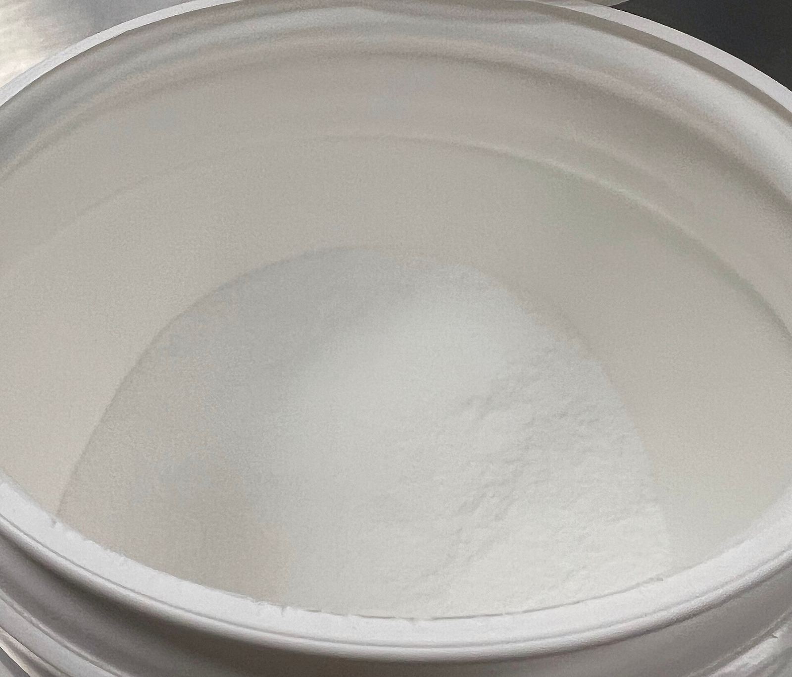 Un pot ouvert de créatine monohydrate, la poudre blanche au fond