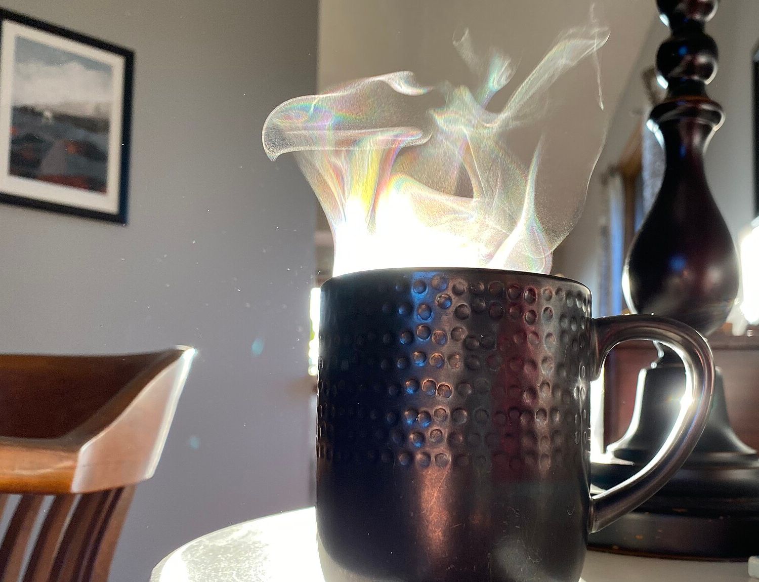 Une tasse de café fumante, à contre-jour, posée sur une petite table