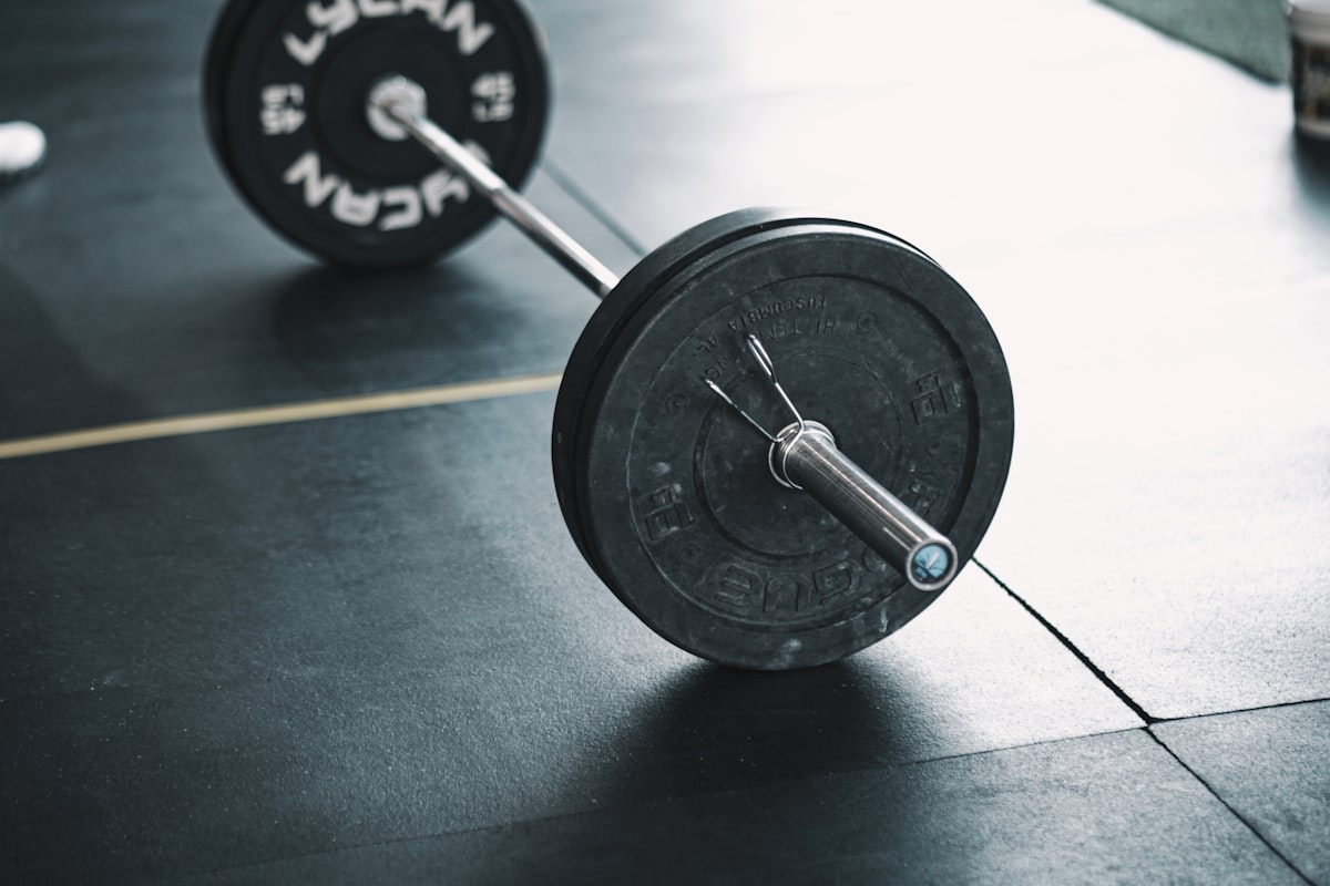 Barre de musculation chargée, posée au sol d'une salle d'entraînement